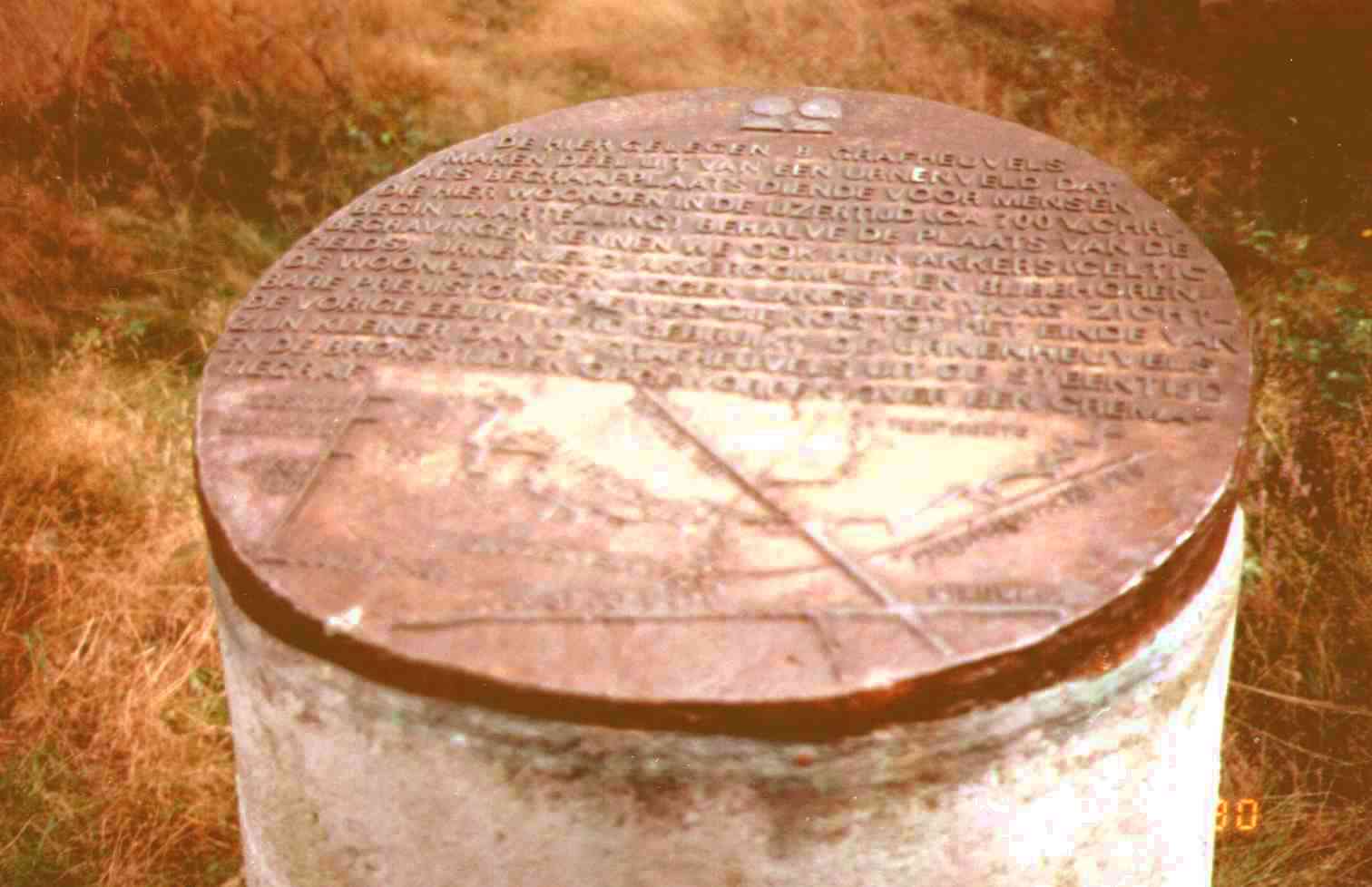 de prehistorische weg loopt ook langs een urnenveld, waar deze betonnen zuil met koperen dekplaat staat (aan de Wildweg)